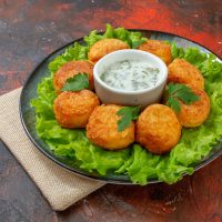 bottom-view-chicken-nuggets-lettuce-sauce-plate-dark-red-table