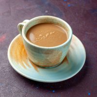 milk-coffee-inside-cup-dark-eggplant-colored-desk